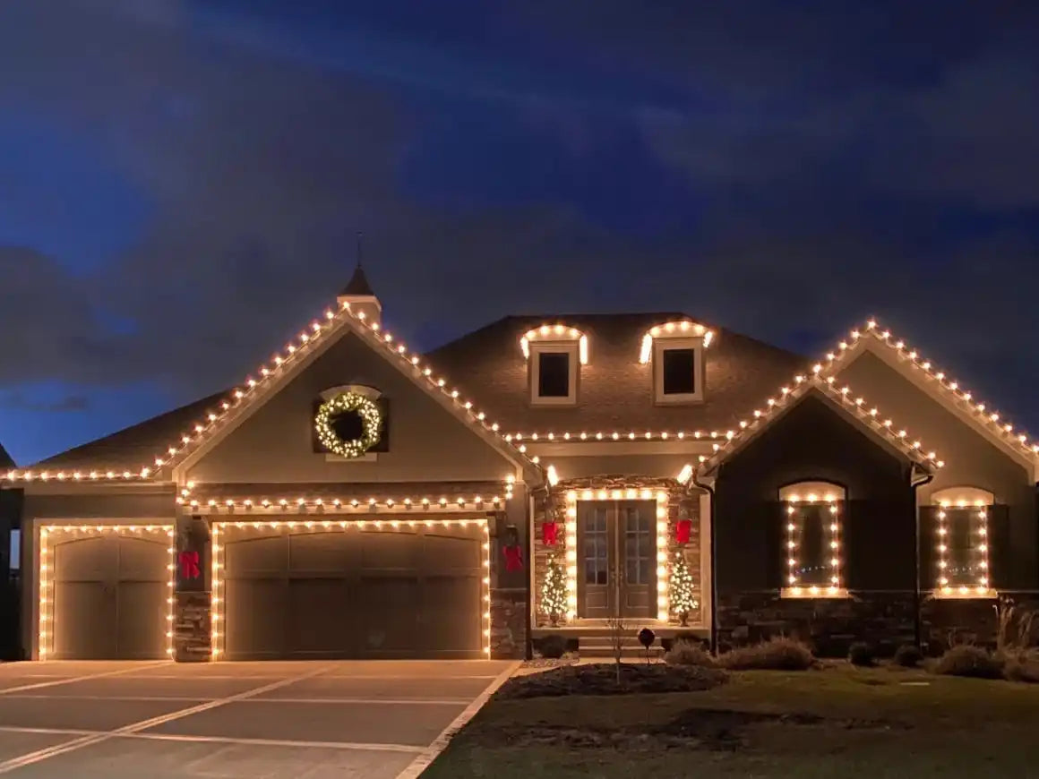 A house beautifully decorated with white Christmas lights and festive wreaths.