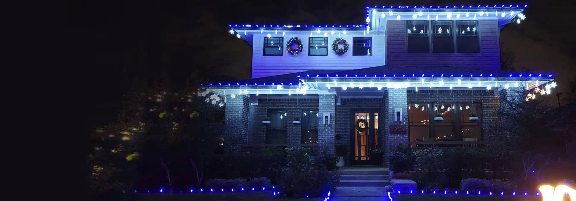 A house decorated with blue and white Christmas lights.