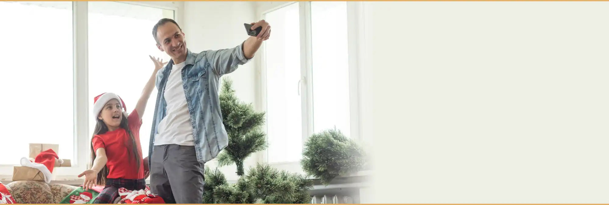 A man and a young girl wearing a Santa hat taking a selfie, surrounded by Christmas decorations and un-assembled artificial Christmas trees.
